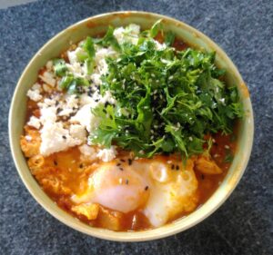 Zubereitung von Shakshuka getoppt mit Koriander und Feta