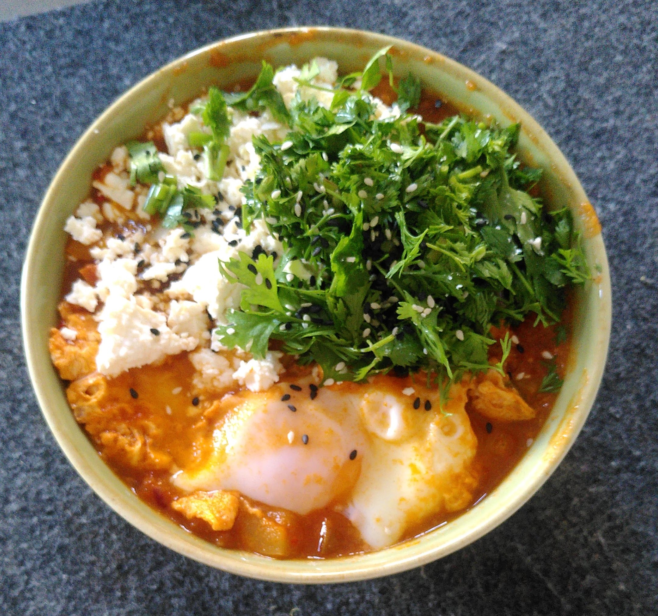 Zubereitung von Shakshuka getoppt mit Koriander und Feta
